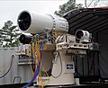 "US_Navy_100119-N-0365D-001_Members_of_the_Directed_Energy_and_Electric_Weapon_Systems_Program_Office_fire_a_laser_through_a_beam_director_on_a_Kineto_Tracking_Mount,_controlled_by_a_MK-15_Phalanx_Close-In_Weapons_System.jpg" by User:BotMultichillT